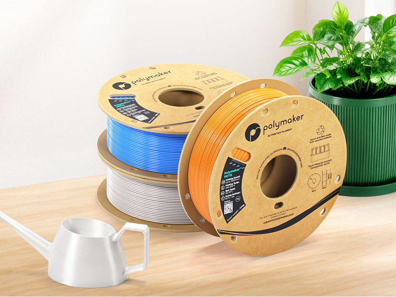 Colored PETG 3D printer filament spools arranged beside a plant